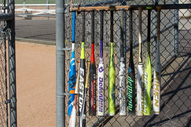 Many different slow-pitch softball bats hanging in the dugout