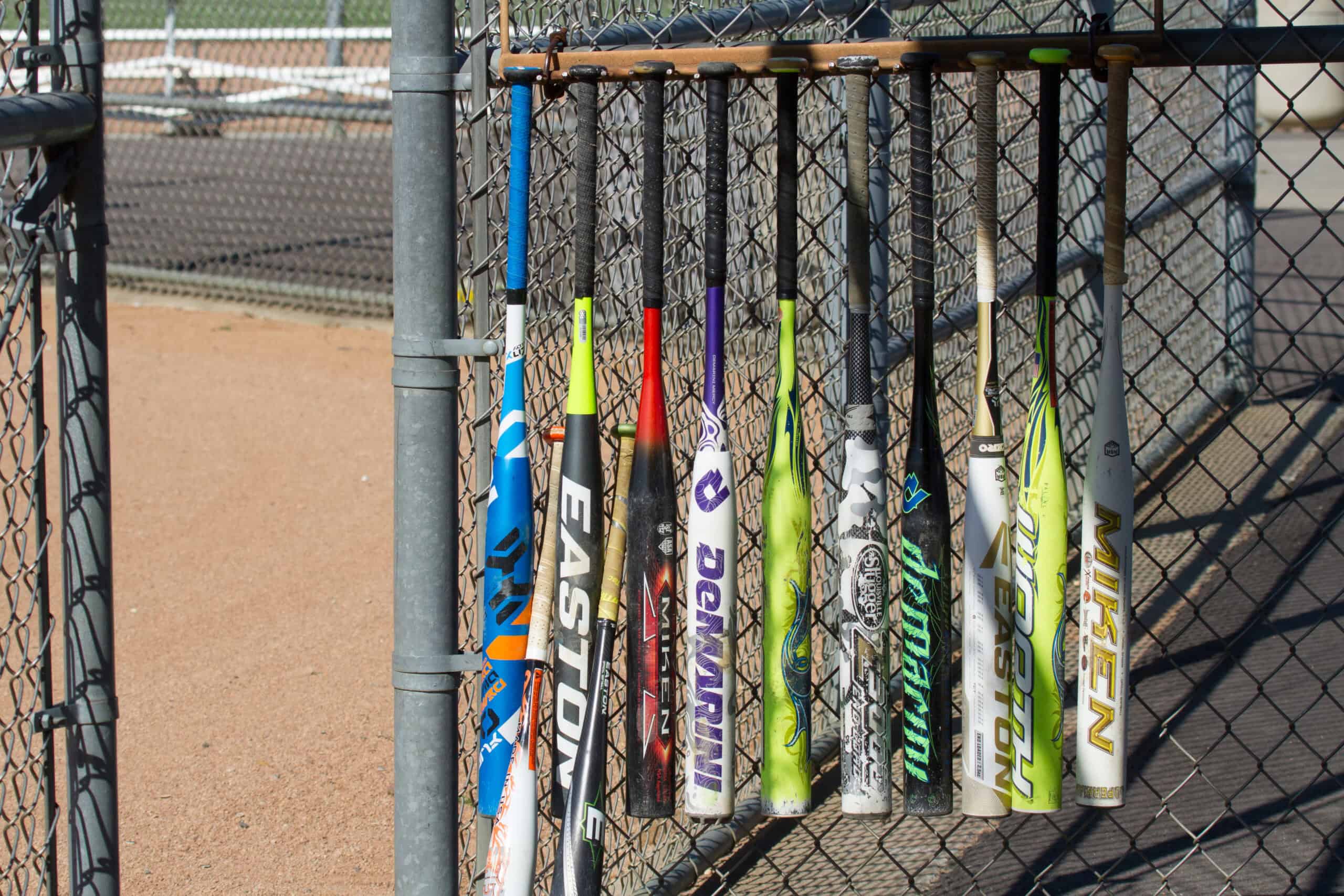 Many different slow-pitch softball bats hanging in the dugout